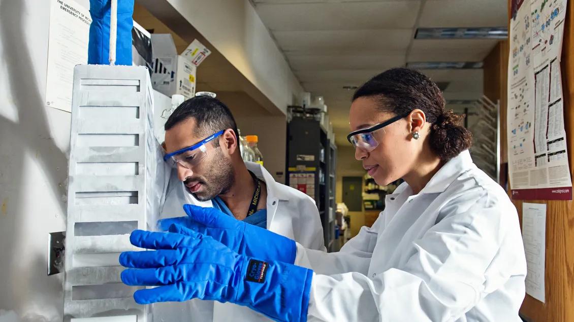 Students wearing white coats and goggles while working