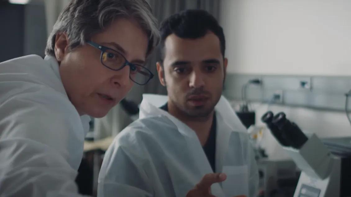 Two people in lab coats looking at something