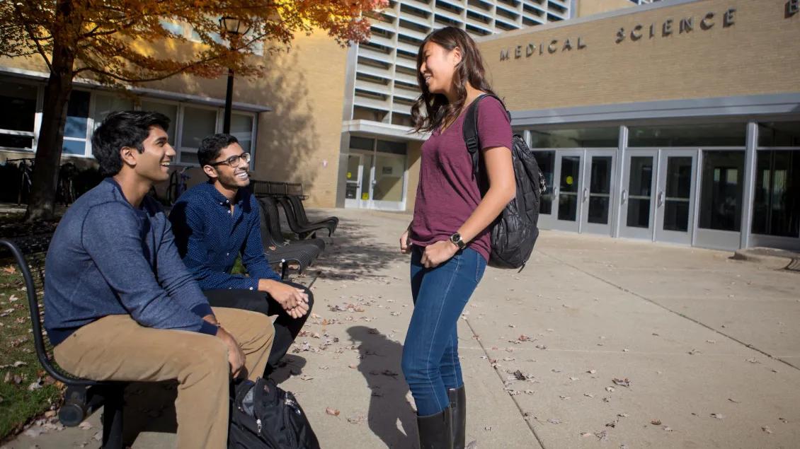 Three people talking outside a medical building on campus