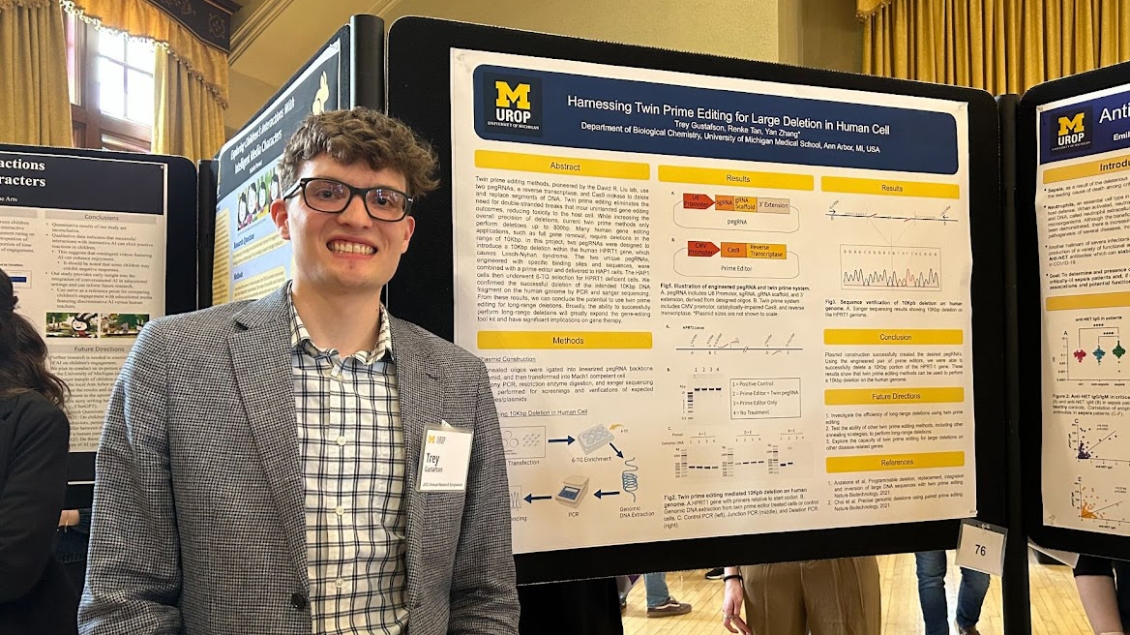 A Biochem student smiles in front of his research poster