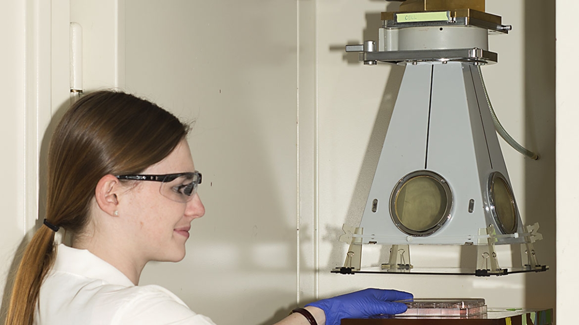 A female radiation oncology researcher uses equipment in the lab