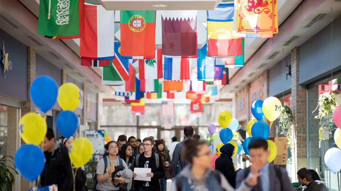 A hallways with international flags and people walking through