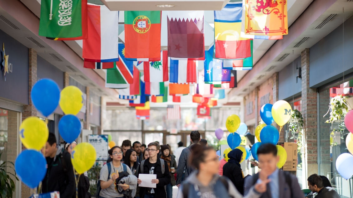 A hallways with international flags and people walking through