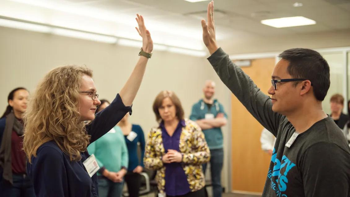 Two people holding one hand in the air facing one another