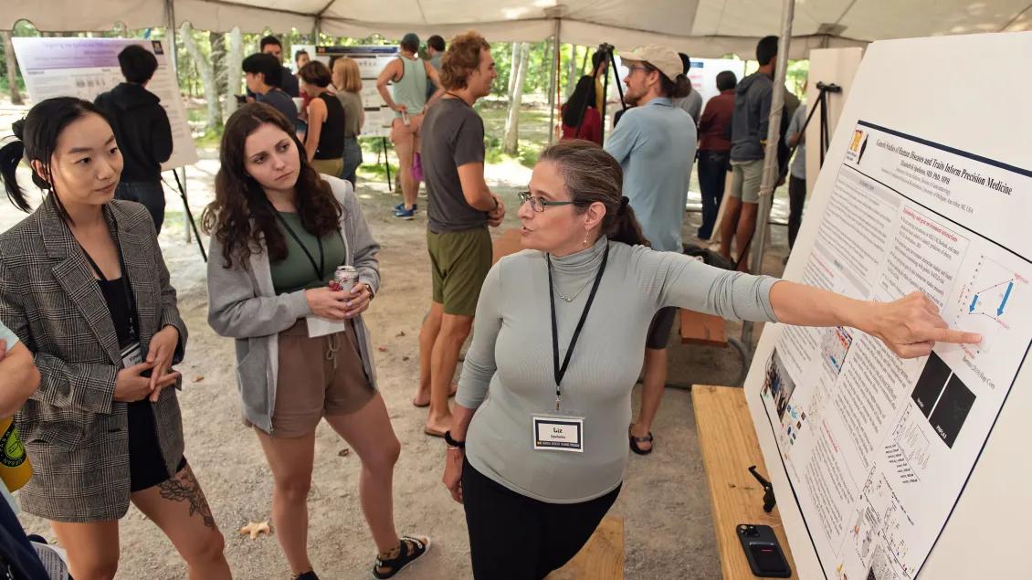 A group of people outside under a tent looking at data on posters