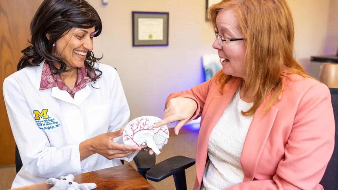 Dr. Shelgikar holds a brain model while speaking with a patient