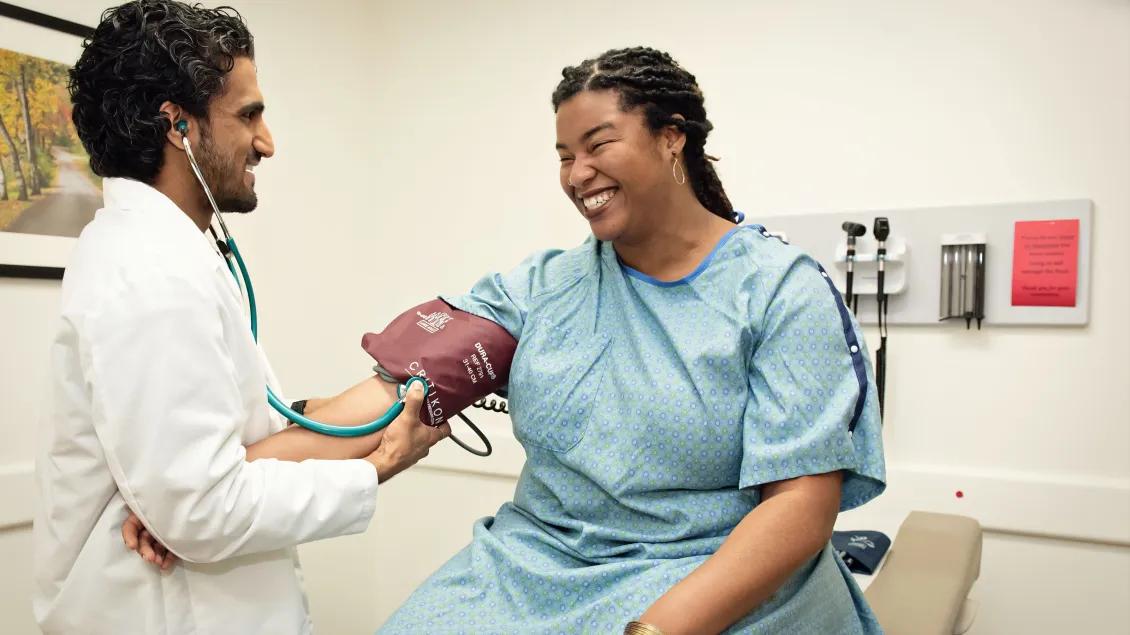 A patient in a room with a doctor taking blood pressure