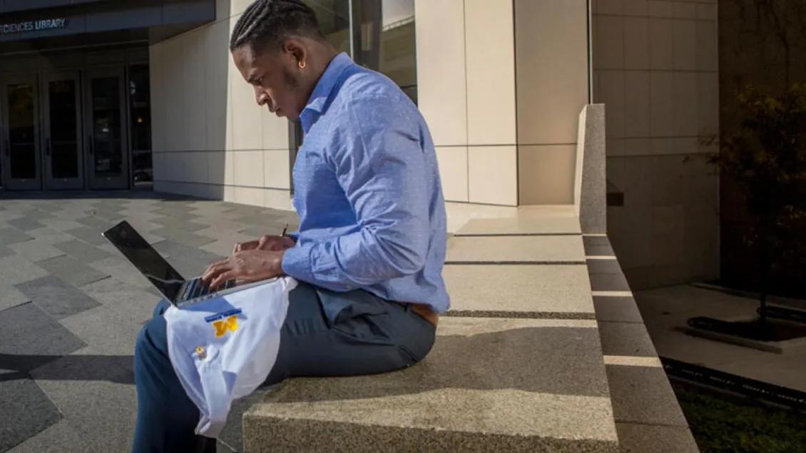 A person sitting outside a campus vuilding
