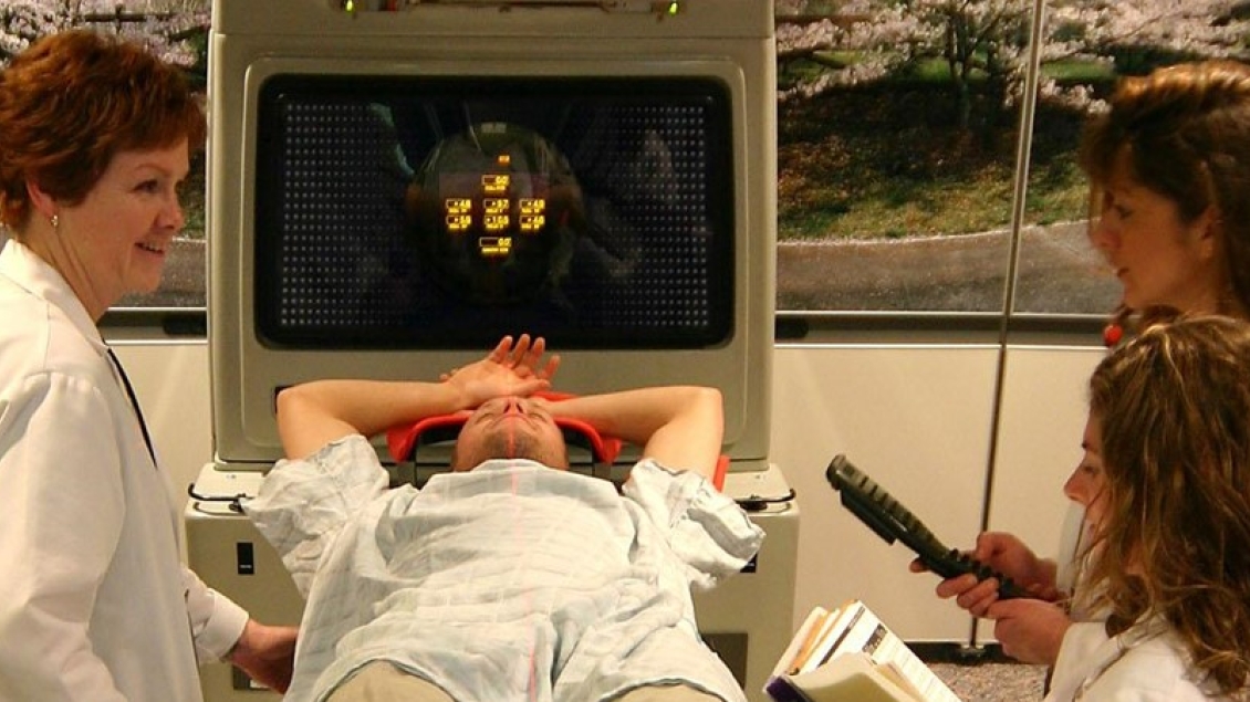 An instructor works with students near a patient 