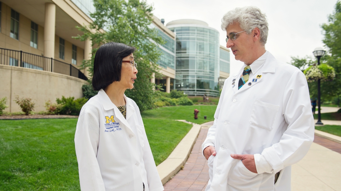 Two people in labcoats having a conversation outside