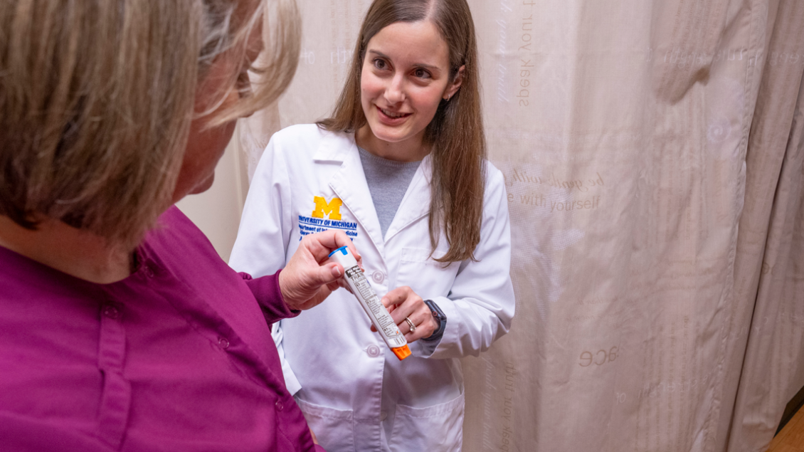 Female doctor points to vial female patient is holding