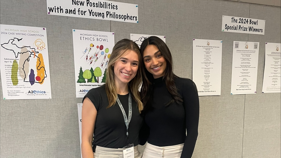 Two medical students standing in front of a bulletin board smiling at camera