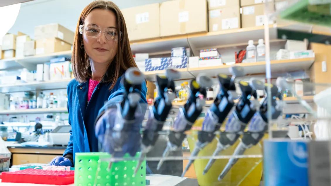 Girl in Gallagher Lab reaching for test tubes 