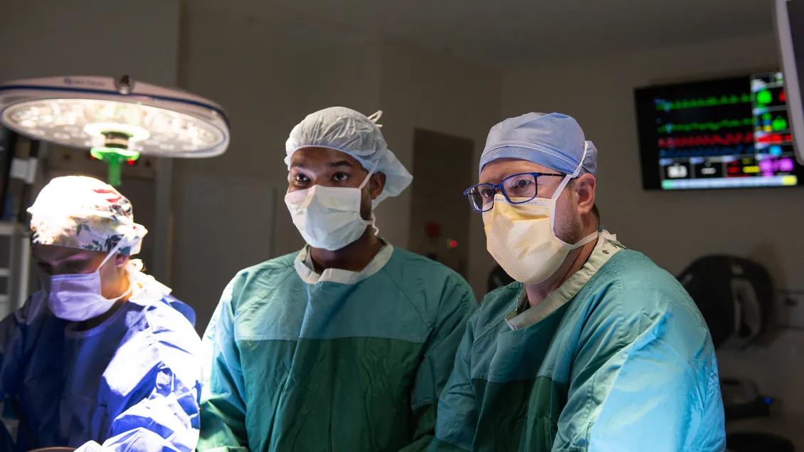 two doctors wearing teal scrubs stand in an operating room 