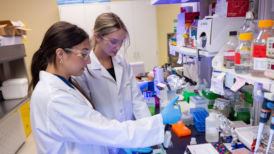 Two girls in g]lab working on project together 