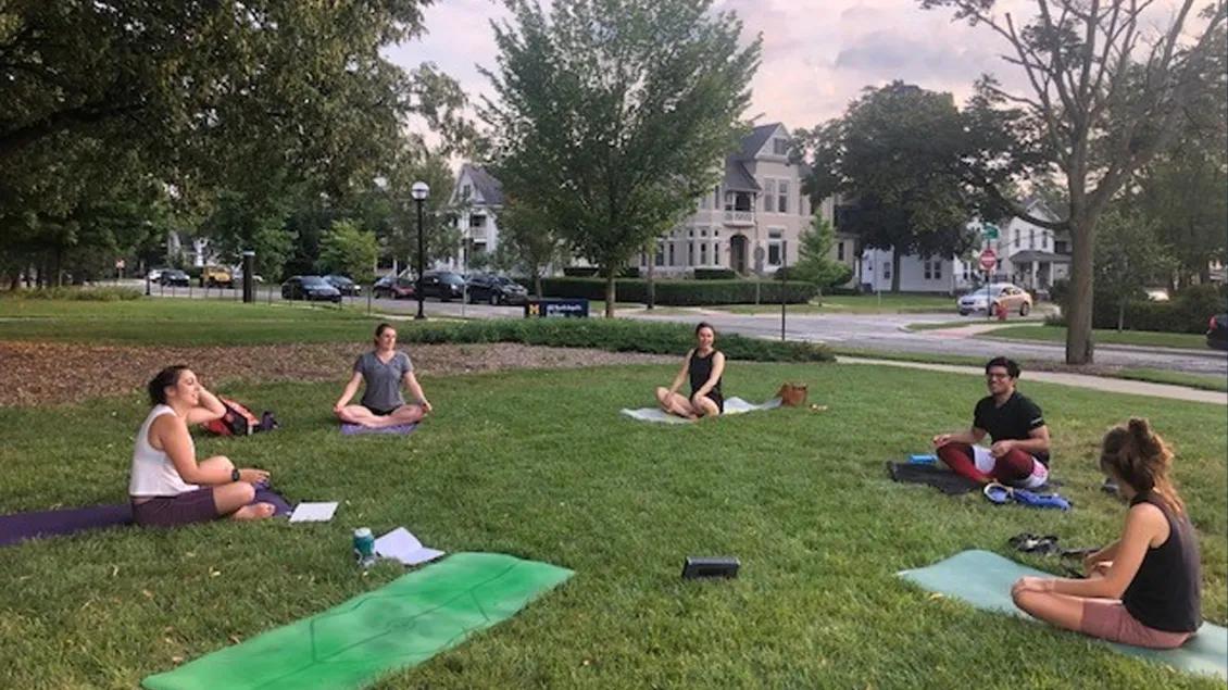 A group of students doing yoga on the lawn