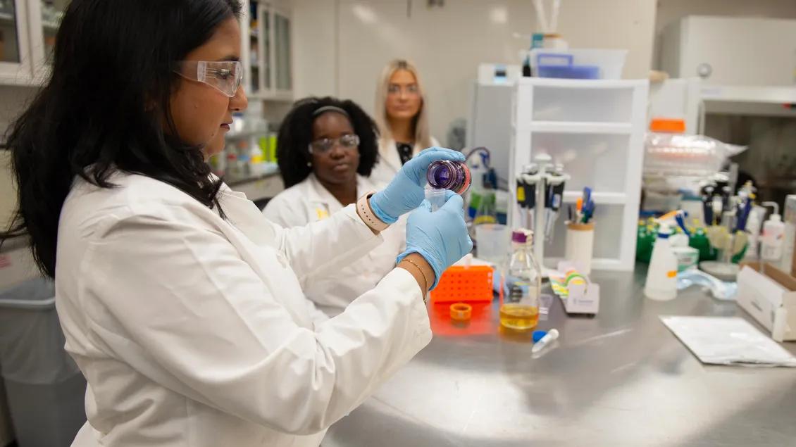 woman holding test tube with other lab helpers
