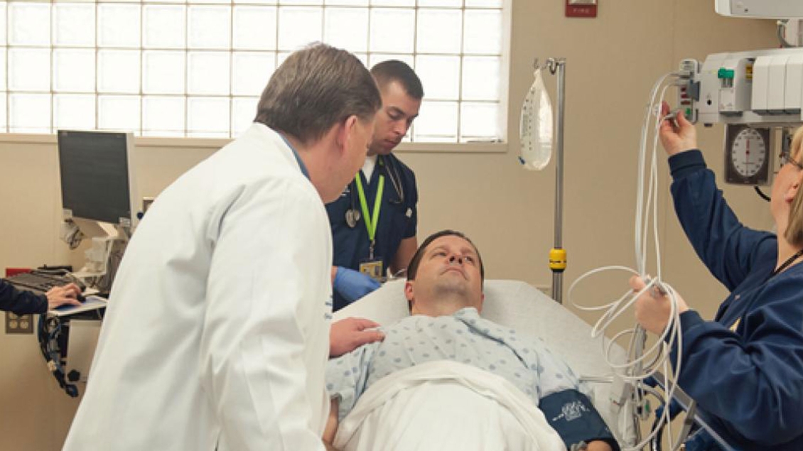 Doctor helps patient that lays in ER bed