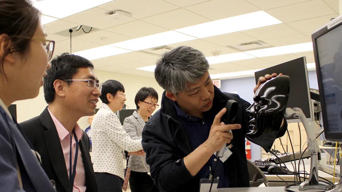 A group of students watching a demonstration on a computer