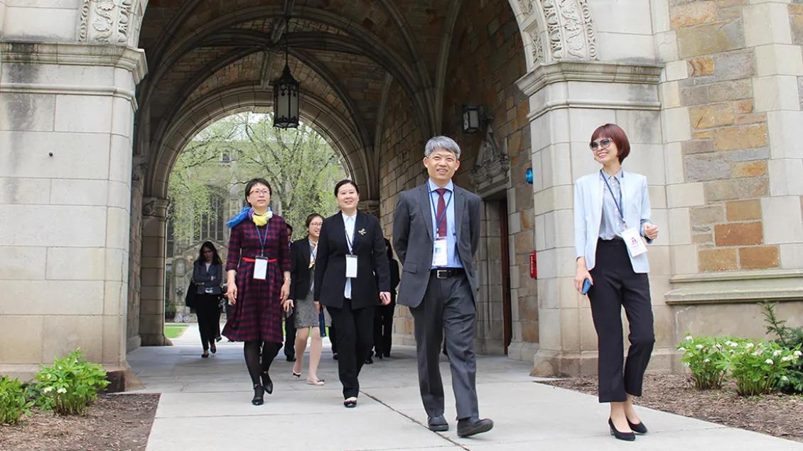 A group of people walking through an arch building outside