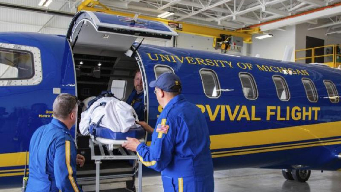 Two emergency medical professionals moving a patient out of a helecopter.