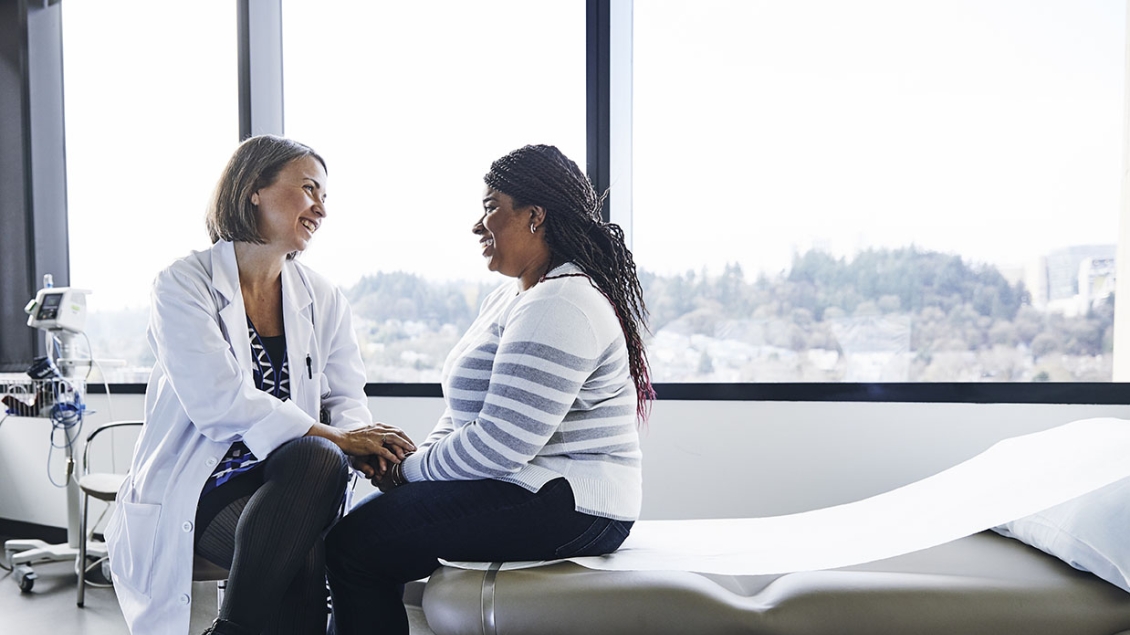 A smiling doctor and patient talk in an exam room.