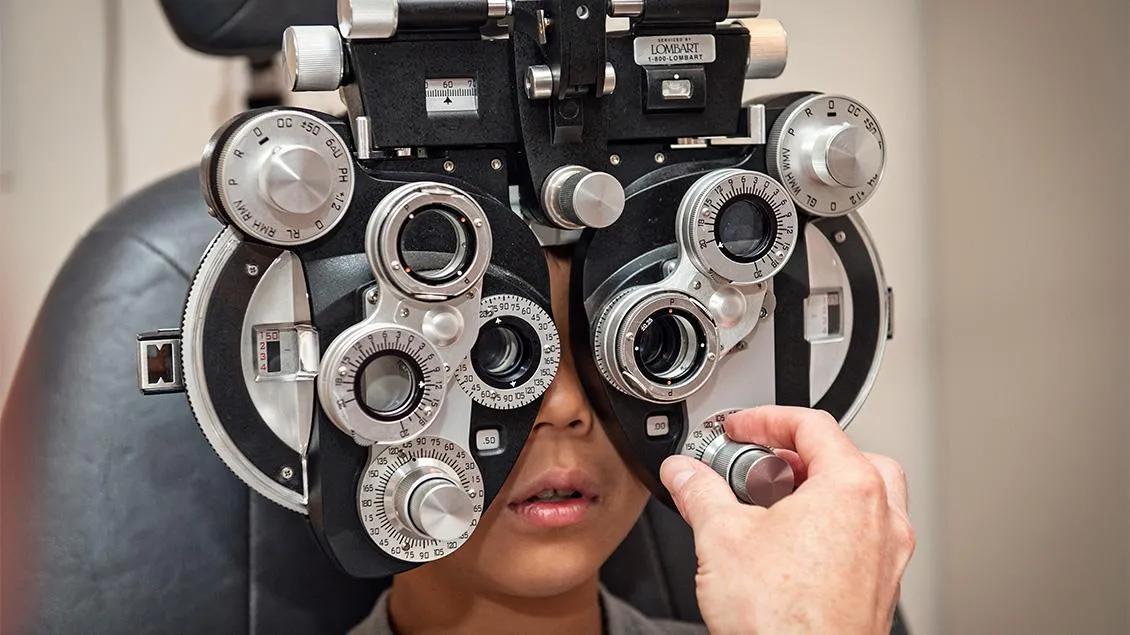 A child looks through eye exam equipment.