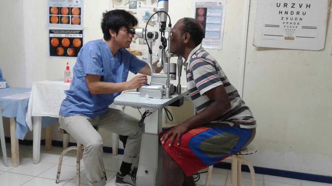 A medical student examines a patient's eyes at a global health clinic
