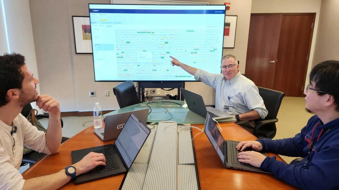 Dr. Hanauer and team in a conference room discussing information on a screen