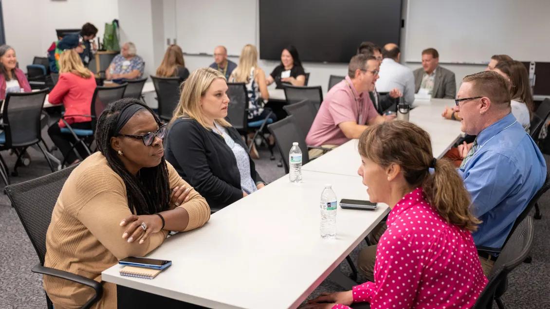 People sitting at tables and talking in a classroom