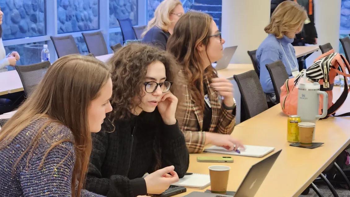 Students talking and looking at a computer in a classroom