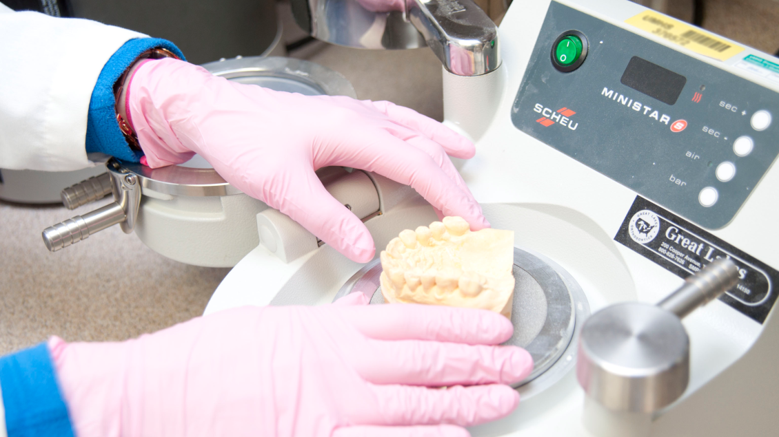 Dr. Munz examines prosthetic teeth with equipment in a lab space