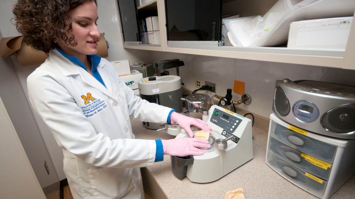 Dr. Munz examines prosthetic teeth with equipment in a lab space