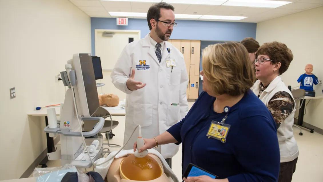 A woman is performing an ultrasound on a mannequin