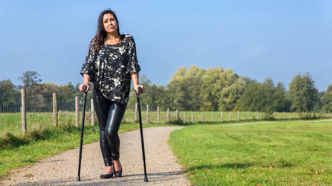 A young woman with disability walks a path with loftstrand crutches