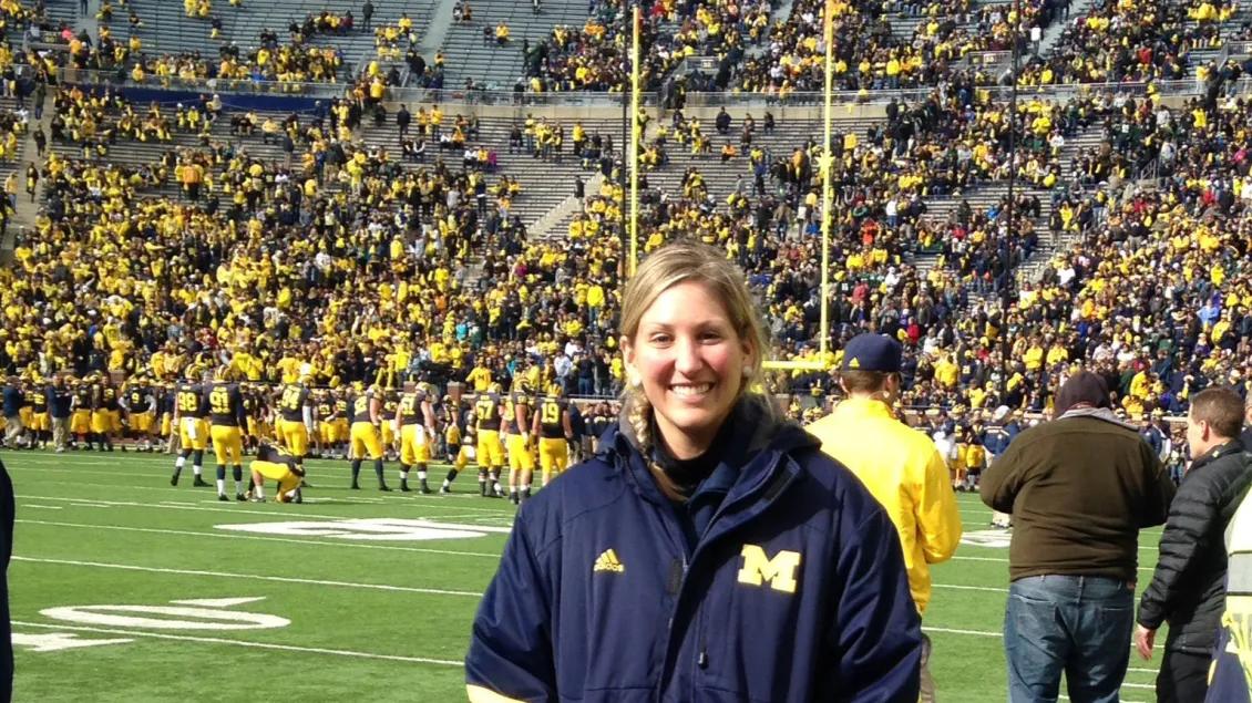 Sports Medicine Fellowship trainee standing on the U-M football field during a game