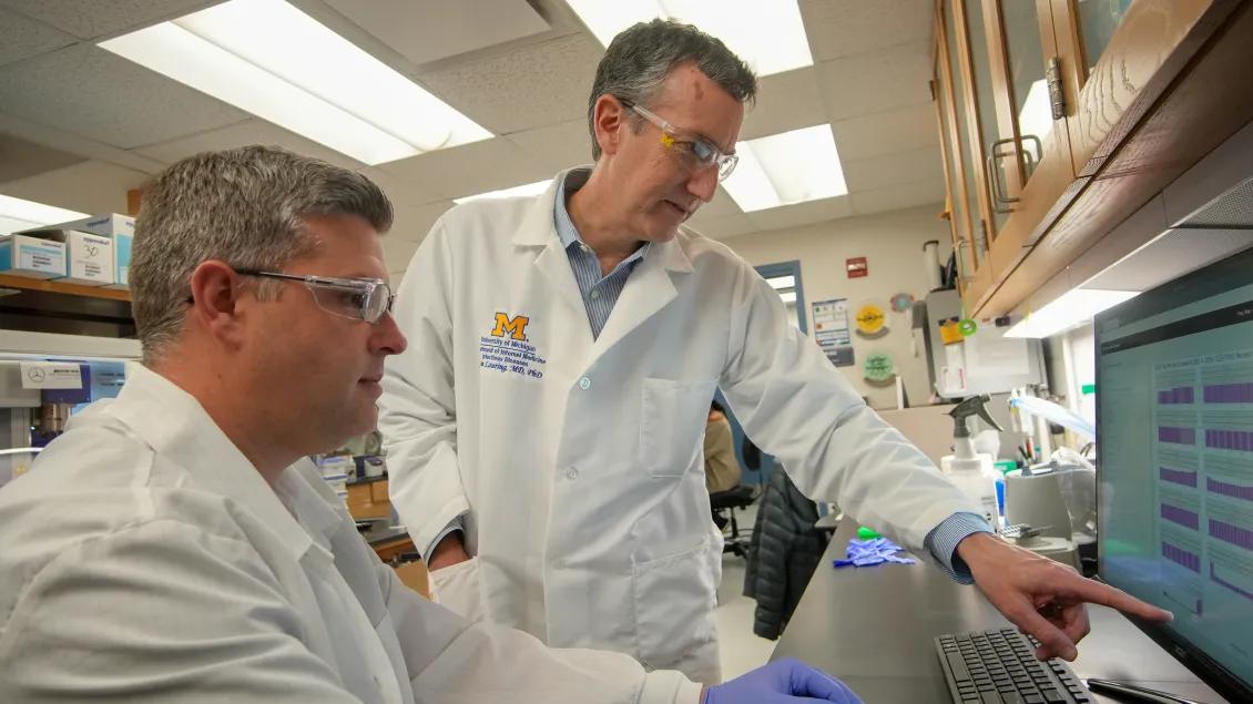dr lauring with other researcher looking at computer