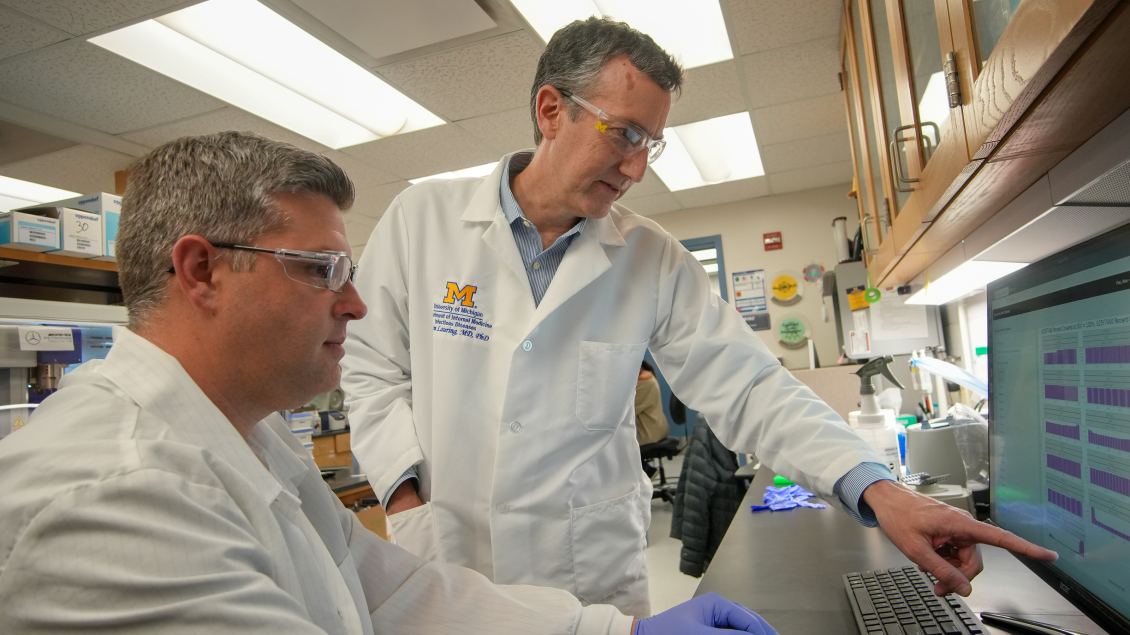 dr lauring with other researcher looking at computer