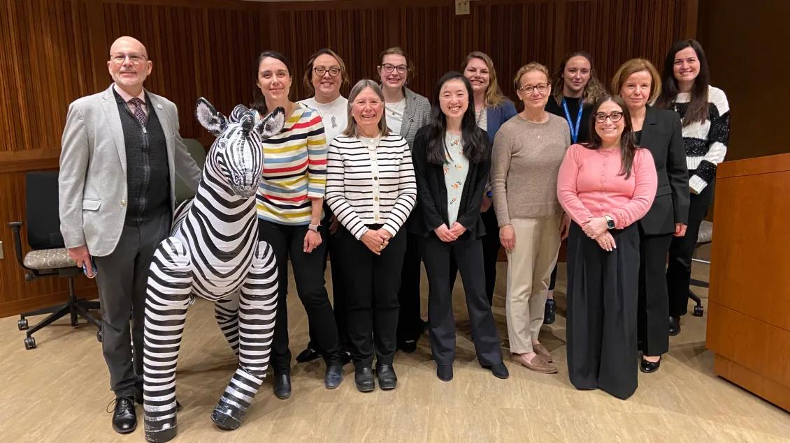 Pediatrics group photo at conference with stuffed zebra to the left.