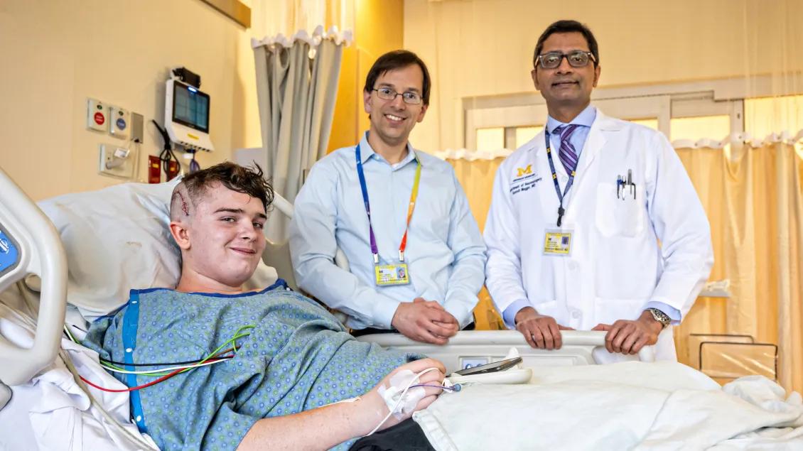 Two physicians stand beside patient in bed posing for photo