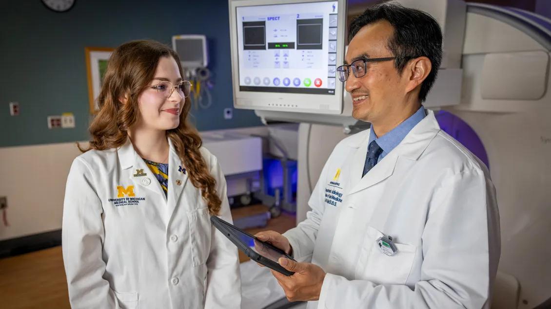 Doctor talks to med student while holding tablet