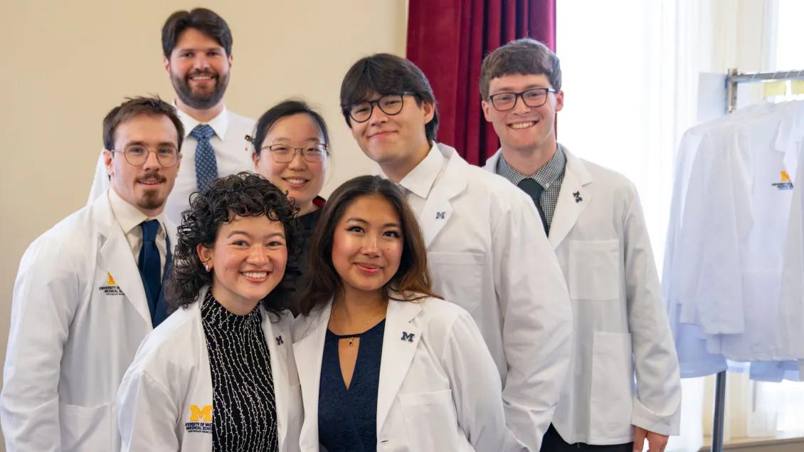 A group of seven medical students wearing white coats