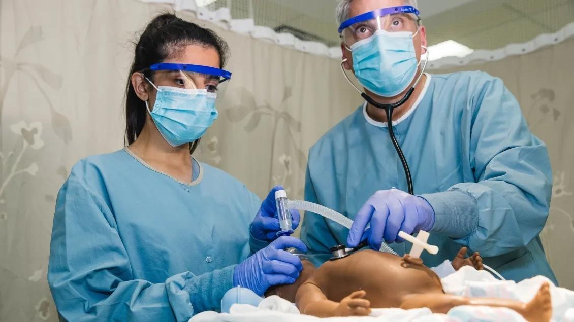 Two doctors perform resuscitation on baby.