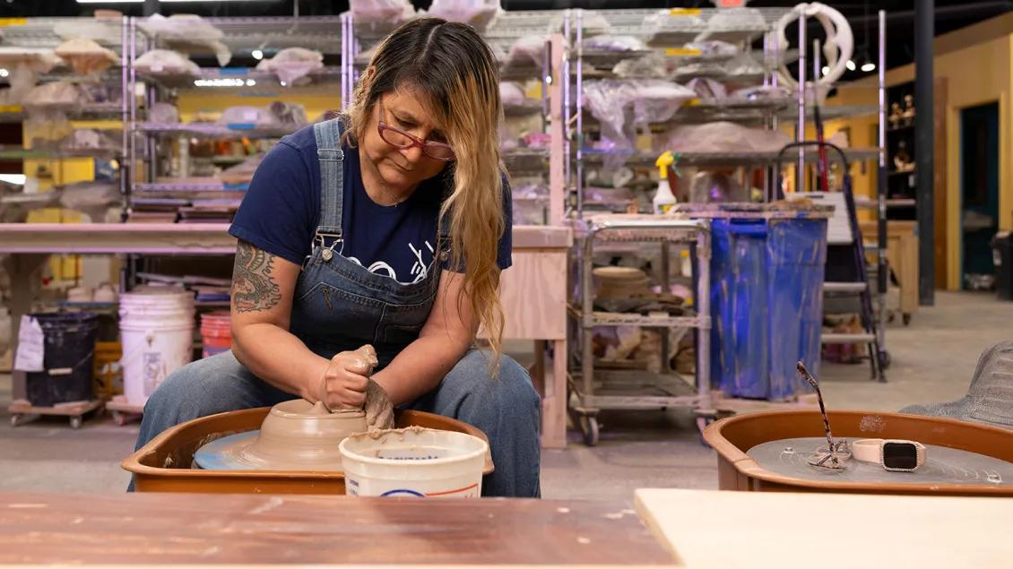 Woman sits at a pottery wheel