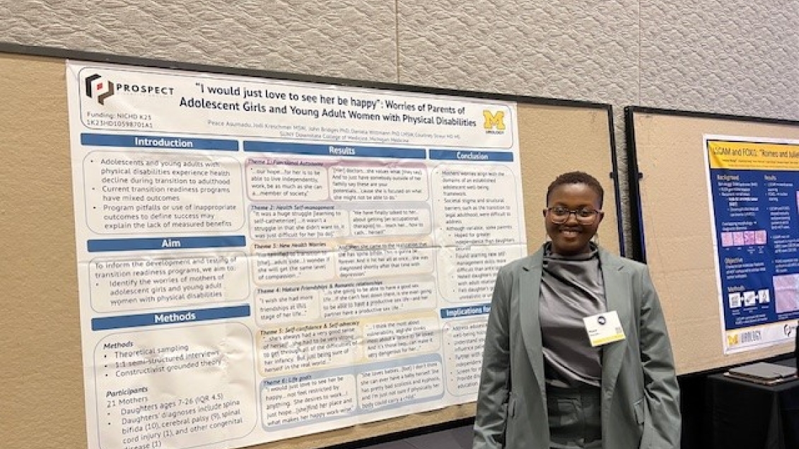 Presenter stands beside a research poster titled ‘I would just love to see her be happy’: worries of parents of adolescent girls and young adult women with physical disabilities