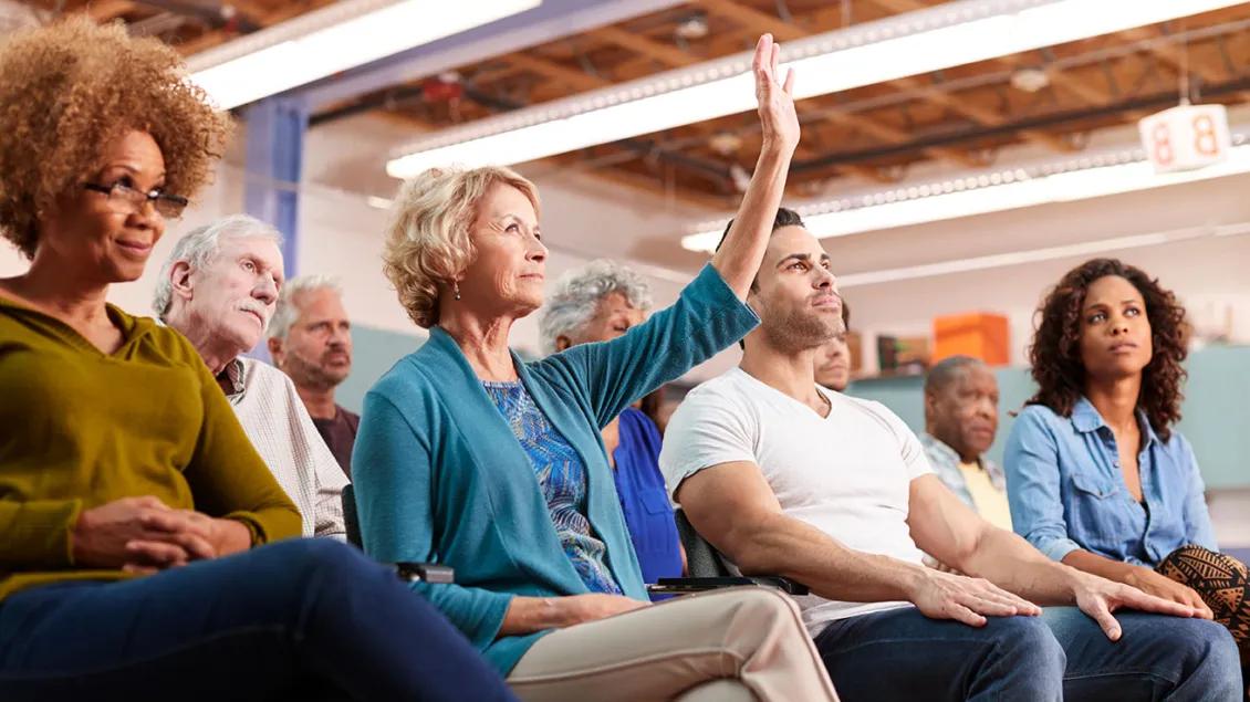 Men, women, young and old sit at a community meeting
