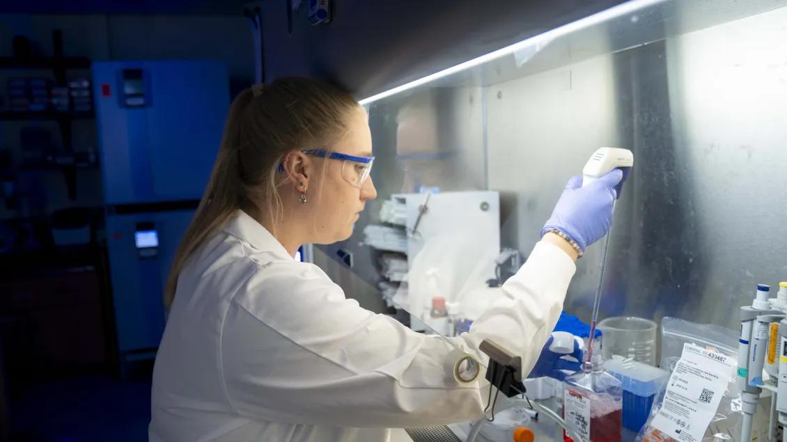 A person working with lab equipment and goggles