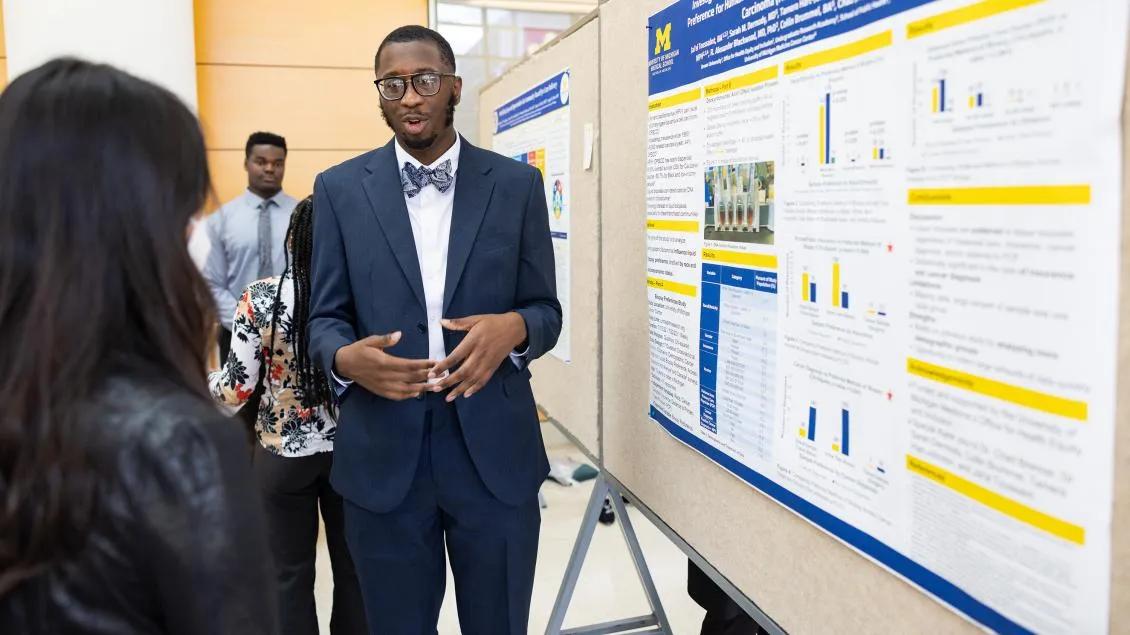 Black male student giving poster presentation