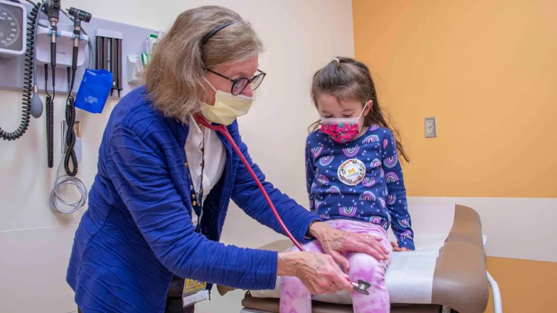 A hospital worker with a pediatrics patient in an exam room