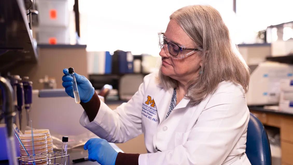 Lab member looking at a test tube